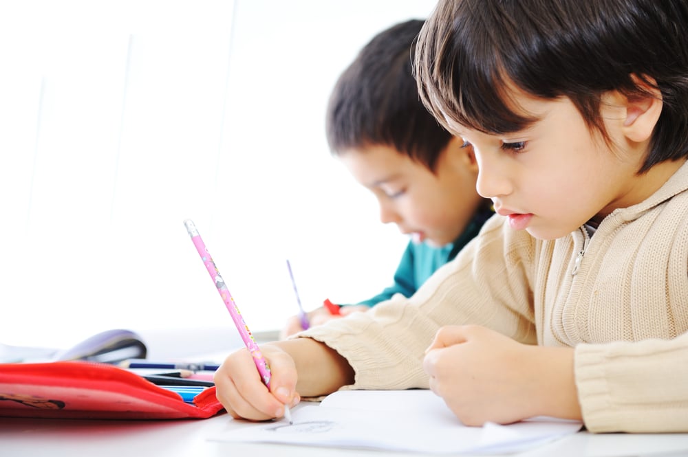 Two cute school boys working on their homework together Two cute school boys working on their homework together